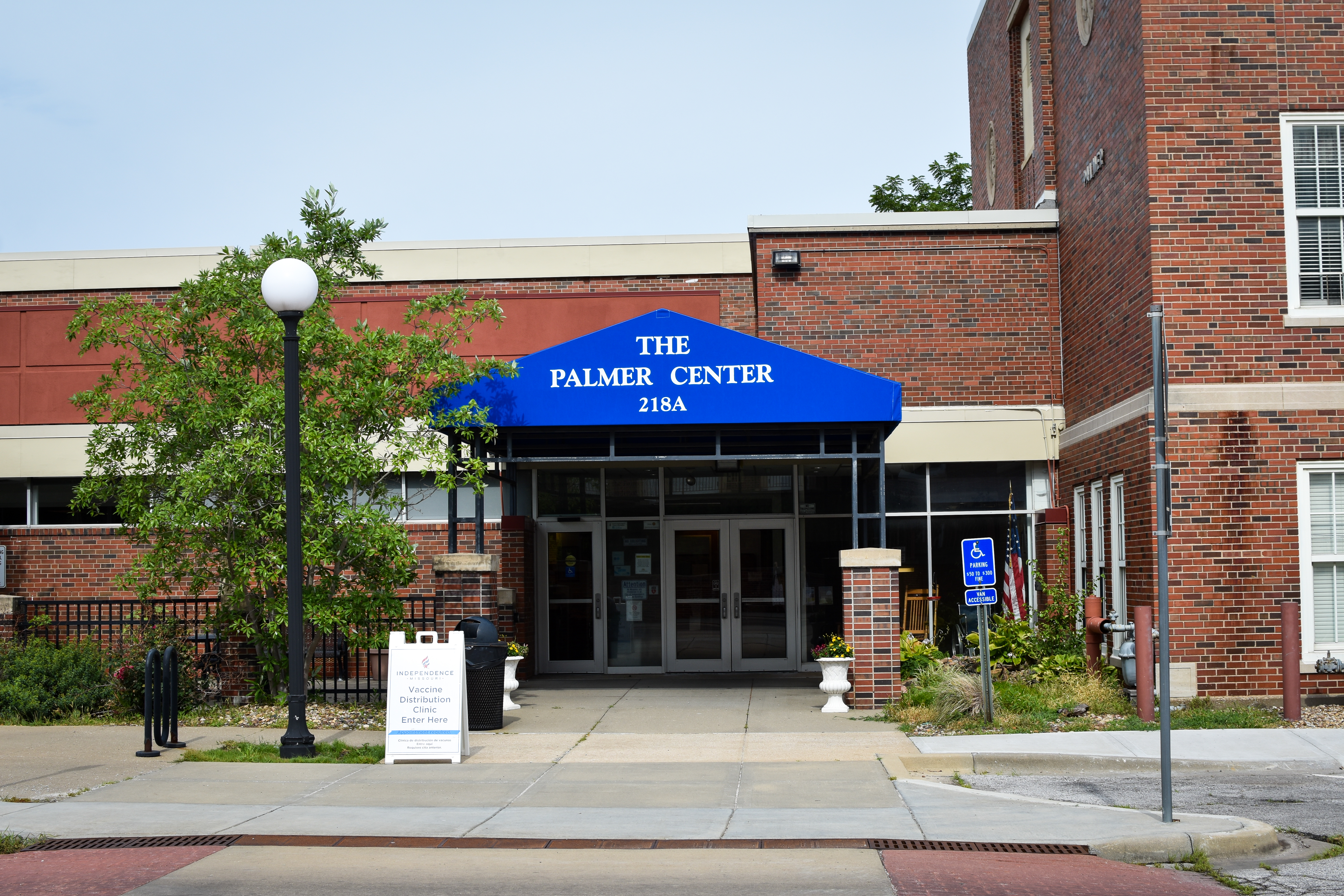 A blue awning sits over the front door of the Palmer Senior Center. It has white words with The Palmer Center 218A printed on it.