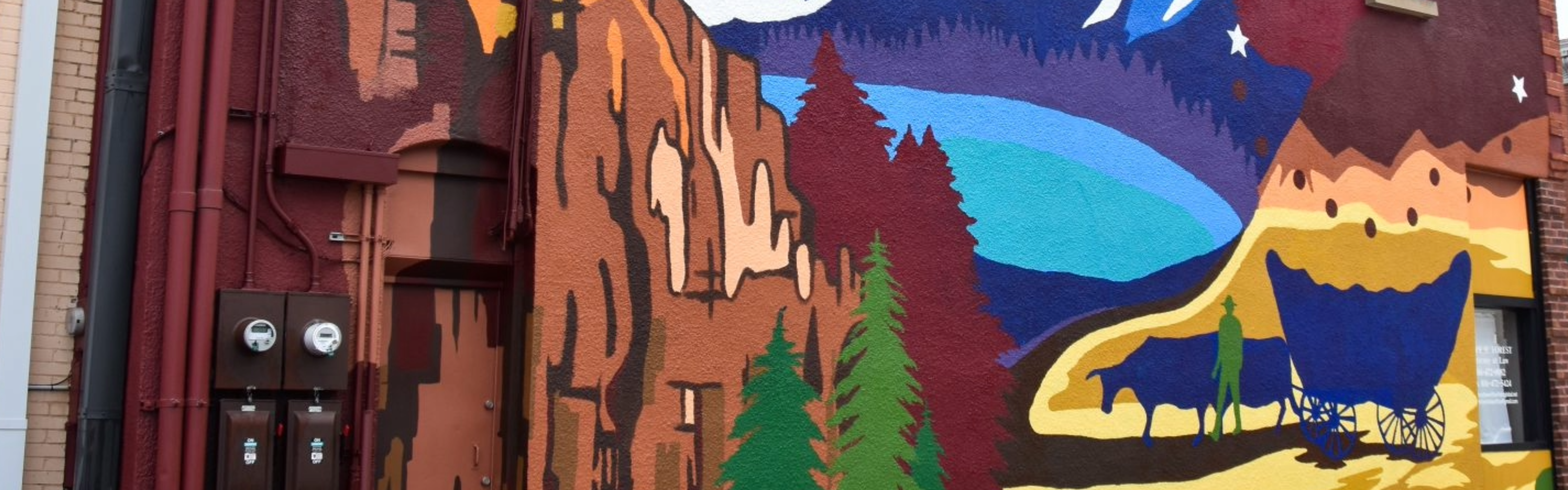 Image of a part of the three trails mural showing a painting of wagon, trail, lake, and trees.