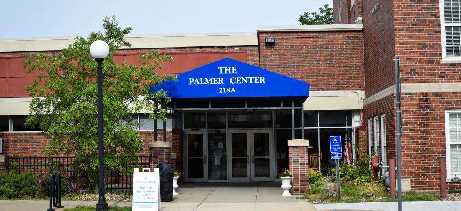 A blue awning sits over the front door of the Palmer Senior Center. It has white words with The Palmer Center 218A printed on it.