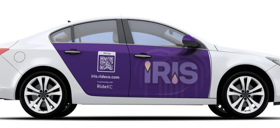 White sedan with a large purple logo over its side doors reading "IRIS"