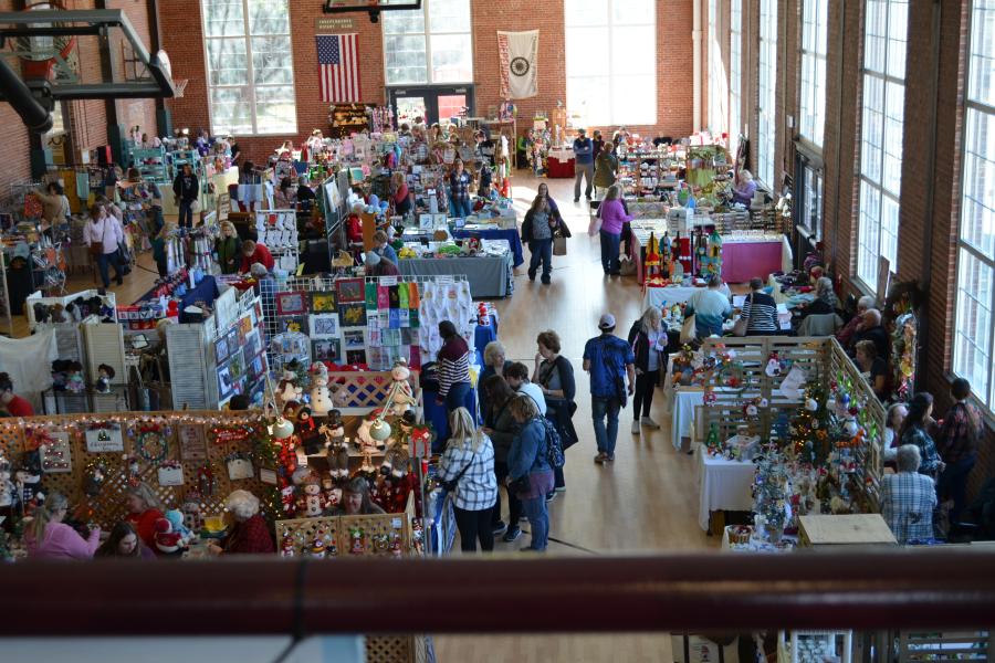 Vendors and shoppers look at holiday crafts and goods on the floor of the Sermon Center basketball court during the Best Little Arts and Crafts Show.