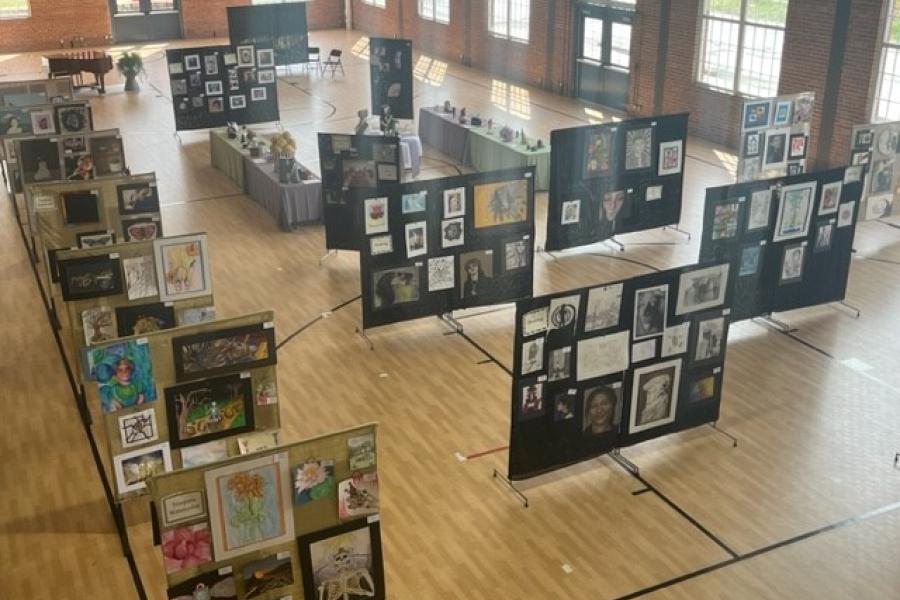 An aerial view looking down onto the Sermon gymnasium where art from area high schools is displayed on art screens at the Youth Art Show in 2023.