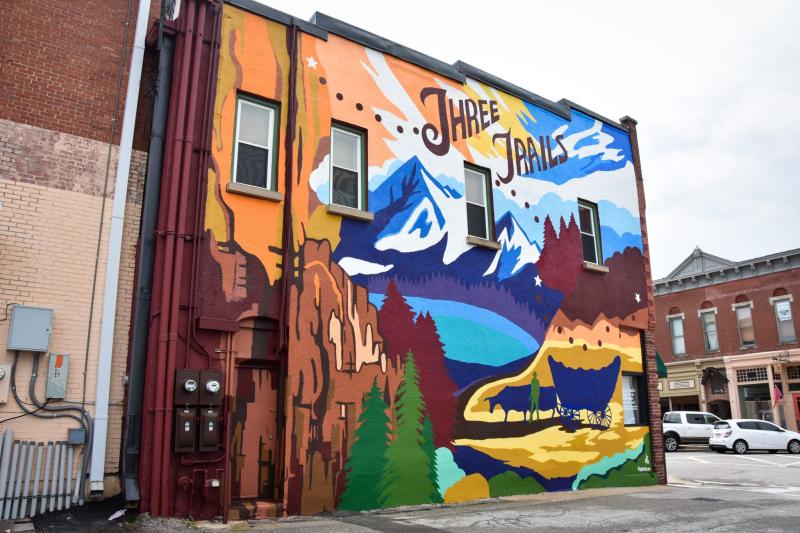 Image of the Three Trails Mural with painting of trails, wagon, lake and trees