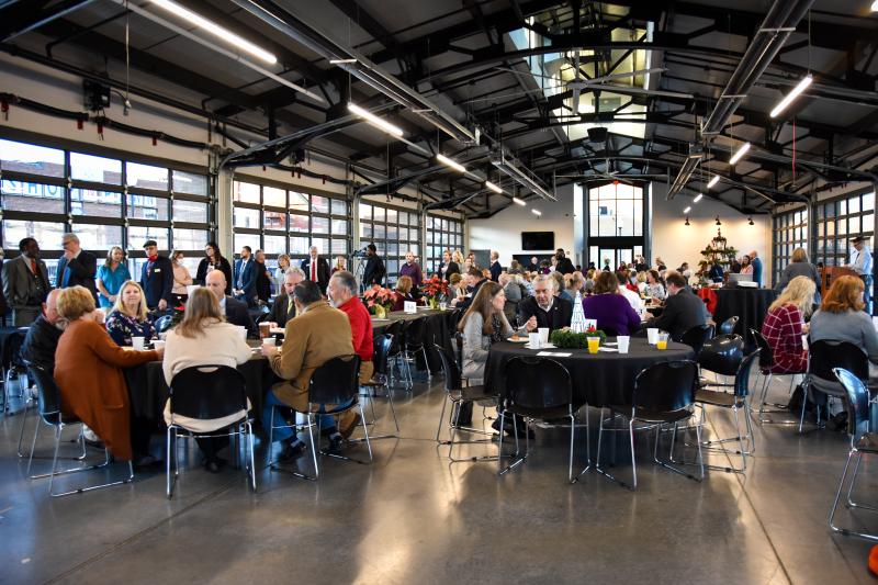 Members of the public sit around round tables with black table clothes inside the Independence Uptown Market.