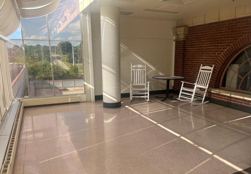 An image of the 4th floor alcove area at the Sermon Center with a table and two white rocking chairs.