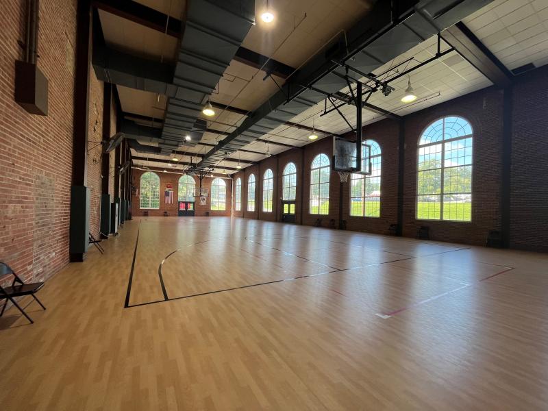 An image of an empty gymnasium space with large windows and brick walls inside the Sermon Center.