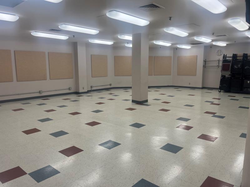 An image of inside the South Meeting Room at the Sermon Center with bright lights, sound boards on the walls and colorful square tiles on the floor.