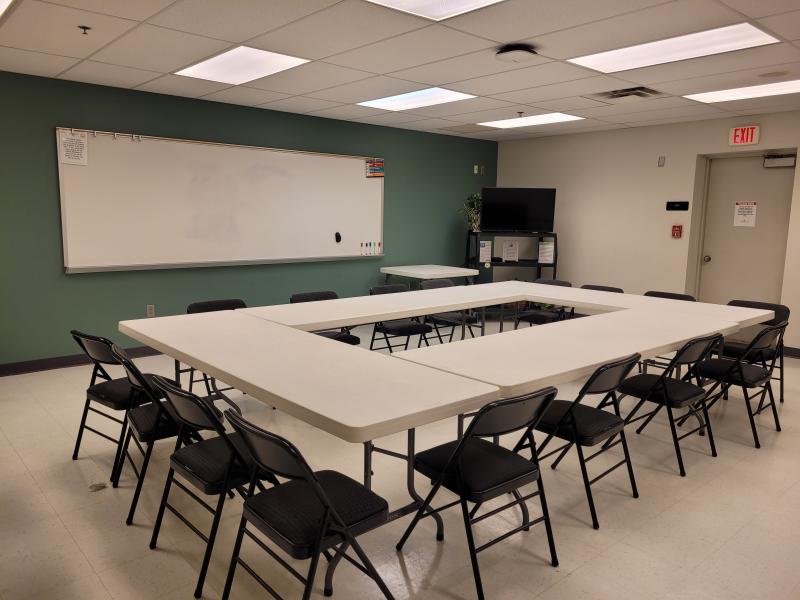 A picture of rectangle tables set up in a square with folding chairs around it inside the Palmer Center Park Place Meeting Room