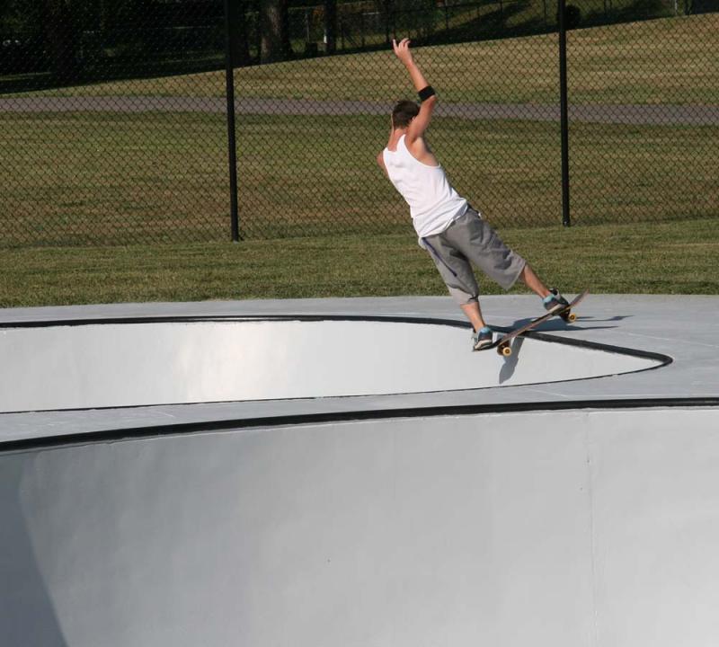 An image of a young man on his skateboard skating at the skate park inside of Hill Park.