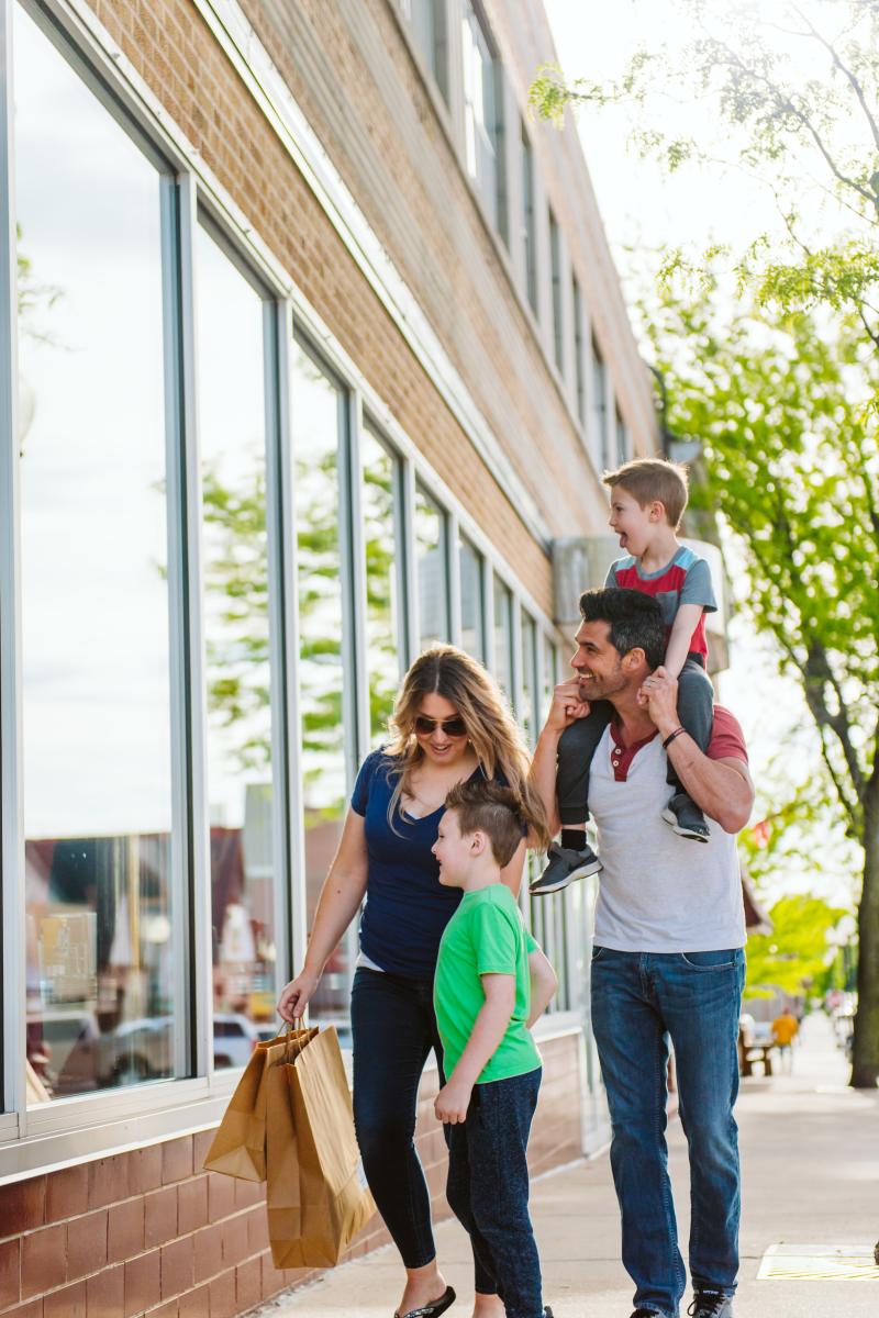 Image of family walking down sidewalk with shopping bags